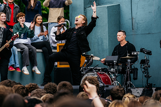 U2結成50周年を記念し、ちょうど50年前にバンドを結成した母校と地元のカフェのバルコニーでサプライズ・ライヴ